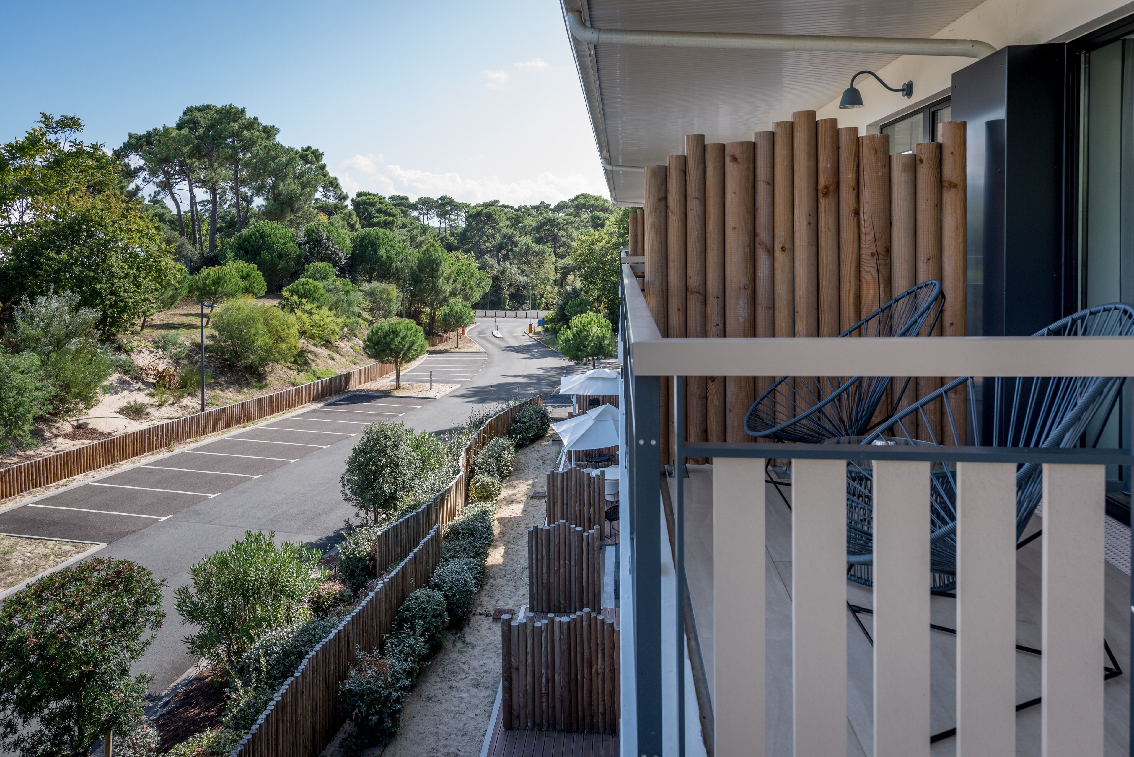 A balcony with a view of a parking lot and trees.