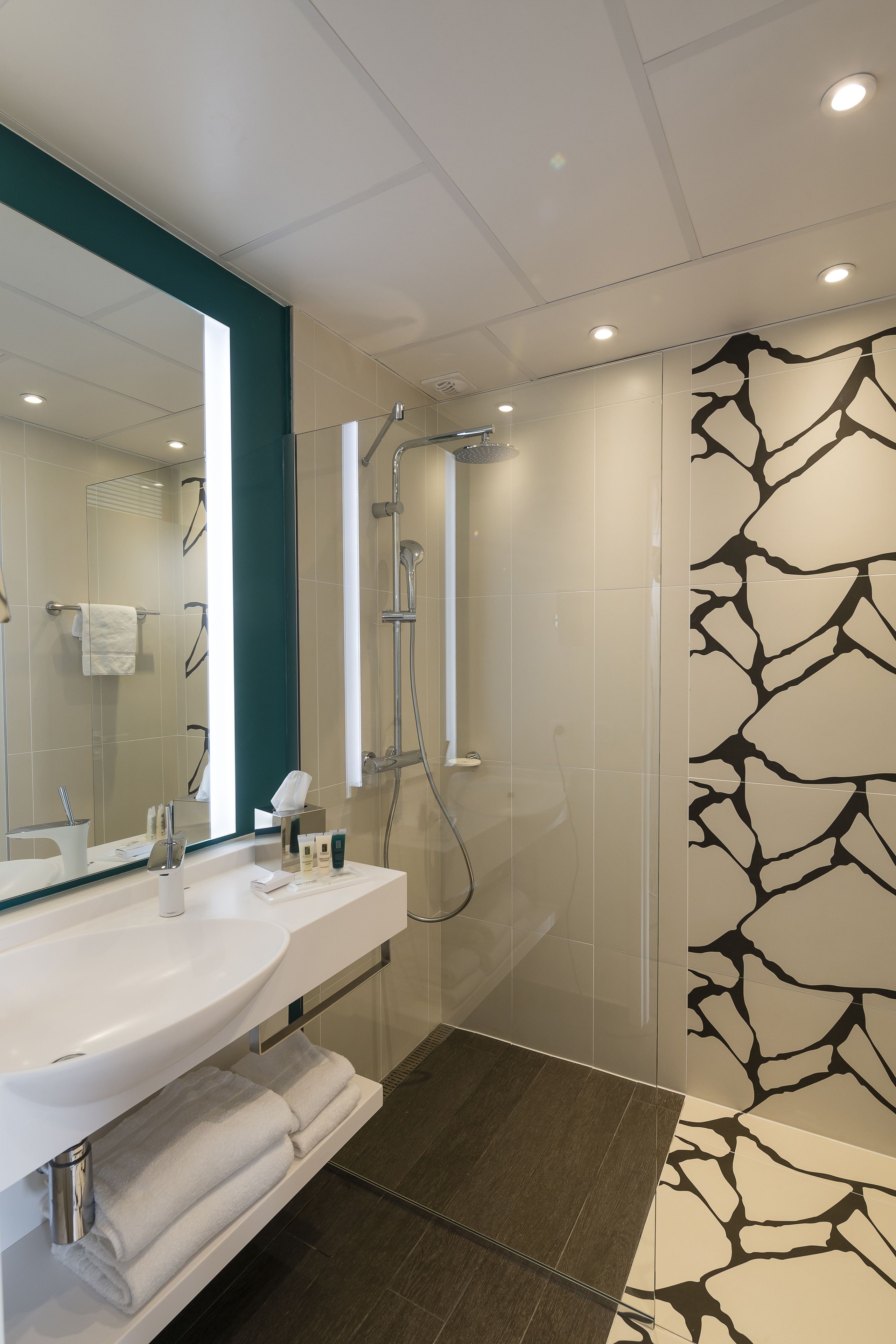 A modern bathroom with a large mirror, a sink, and a shower area.