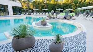 A pool area with lounge chairs, umbrellas, and potted plants. - Hôtel & Spa - Thalazur Arcachon (Arcachon)
