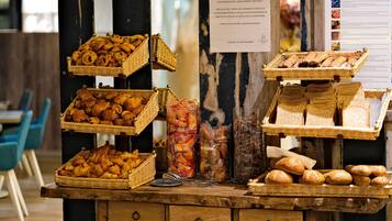A display of various baked goods, including croissants and bread, arranged on a wooden counter with baskets and jars.