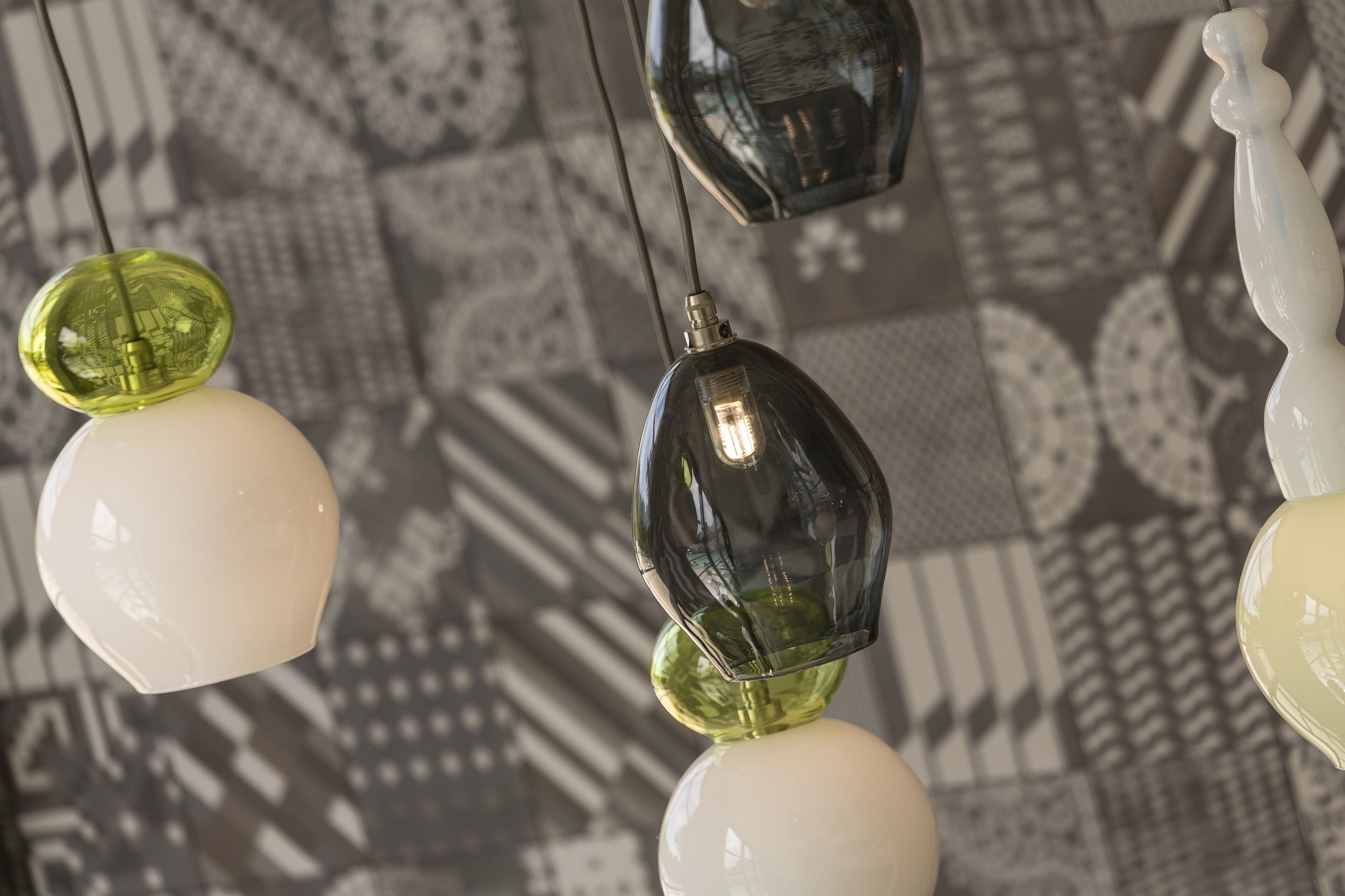 A close-up of hanging pendant lights with a geometric pattern in the background.