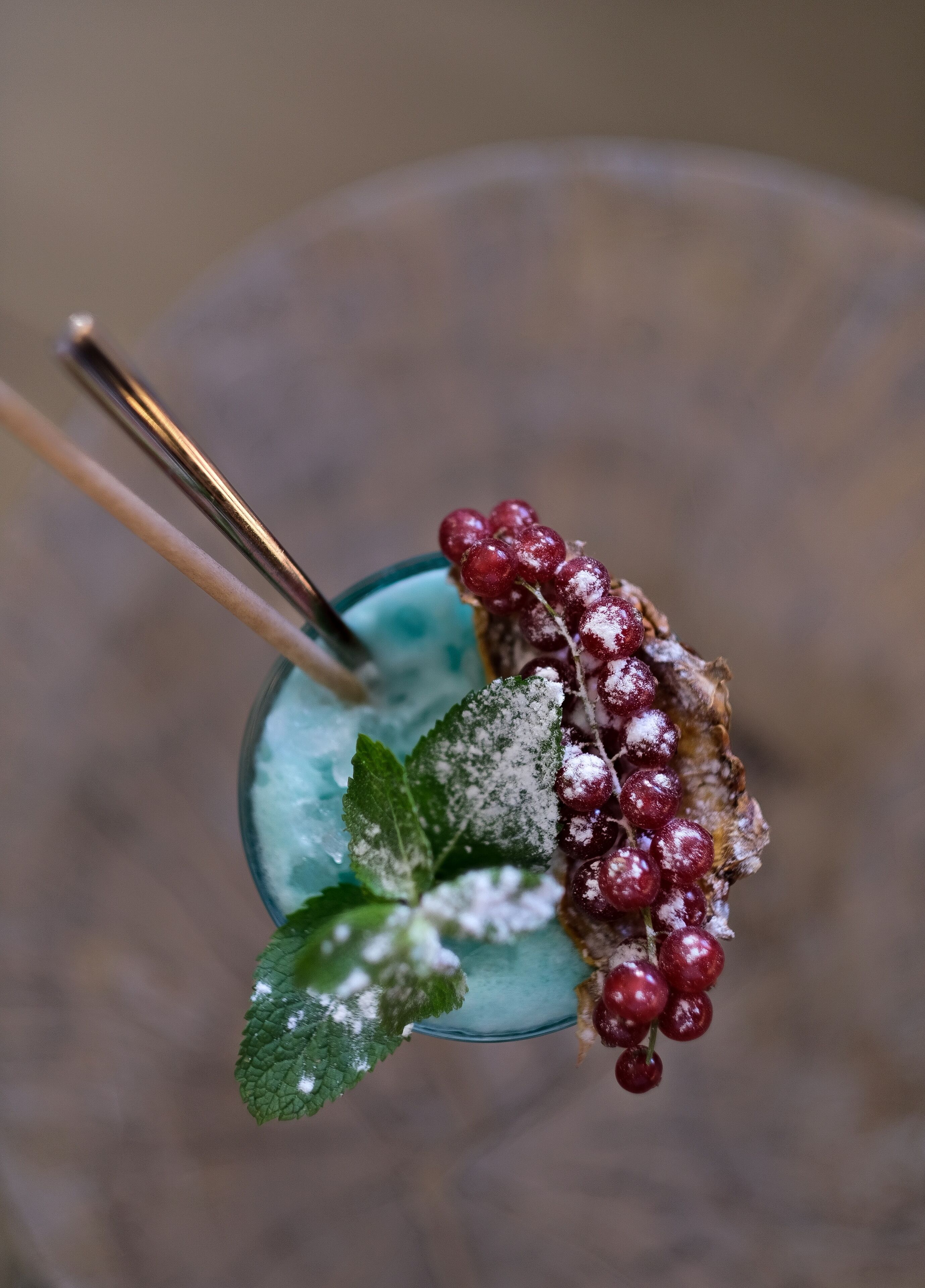 Ein Nahaufnahme eines Cocktails mit Minzblatt-Garnitur und roten Beeren.