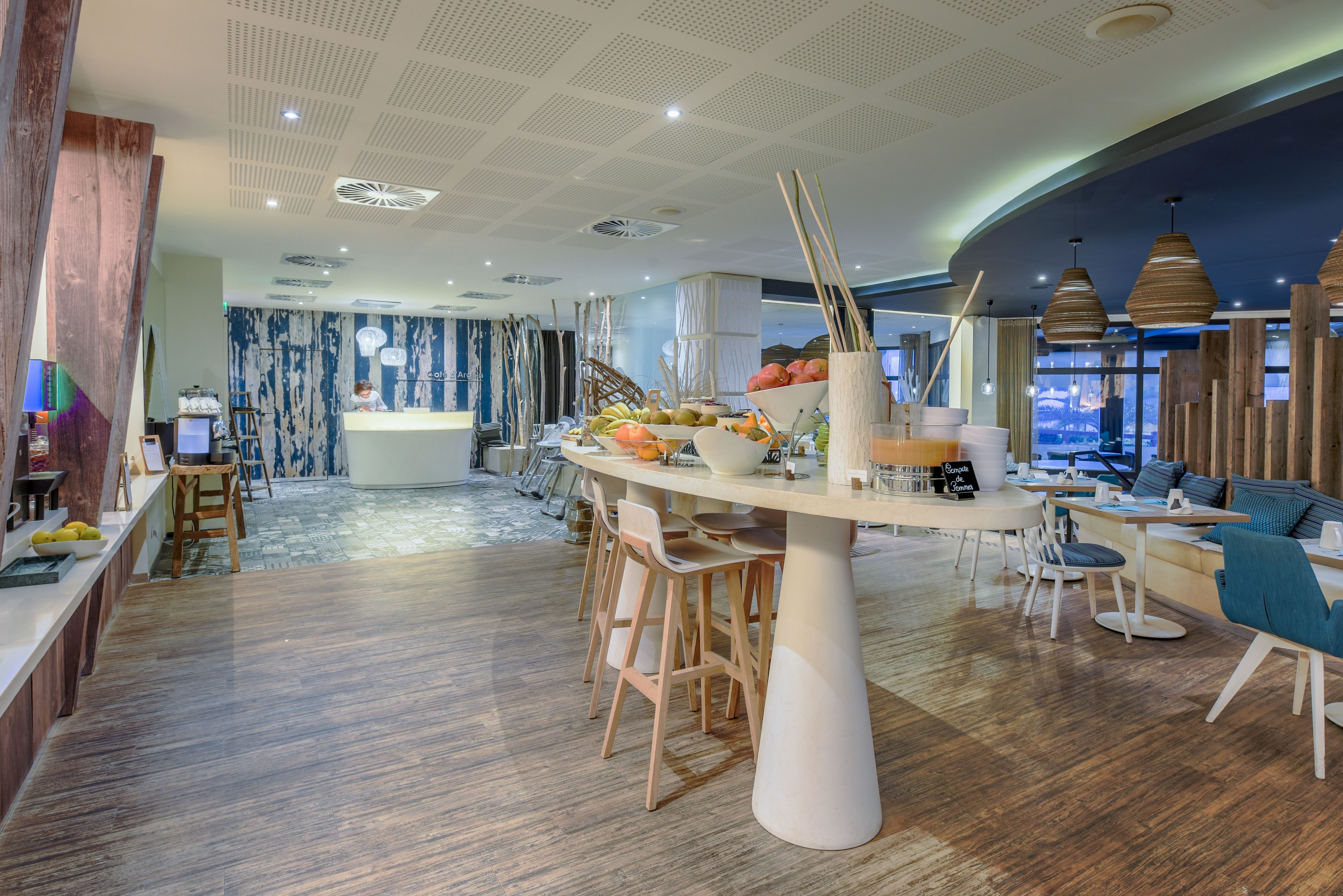 Un restaurant moderne doté d’un îlot central, de chaises en bois et d’un espace bar.