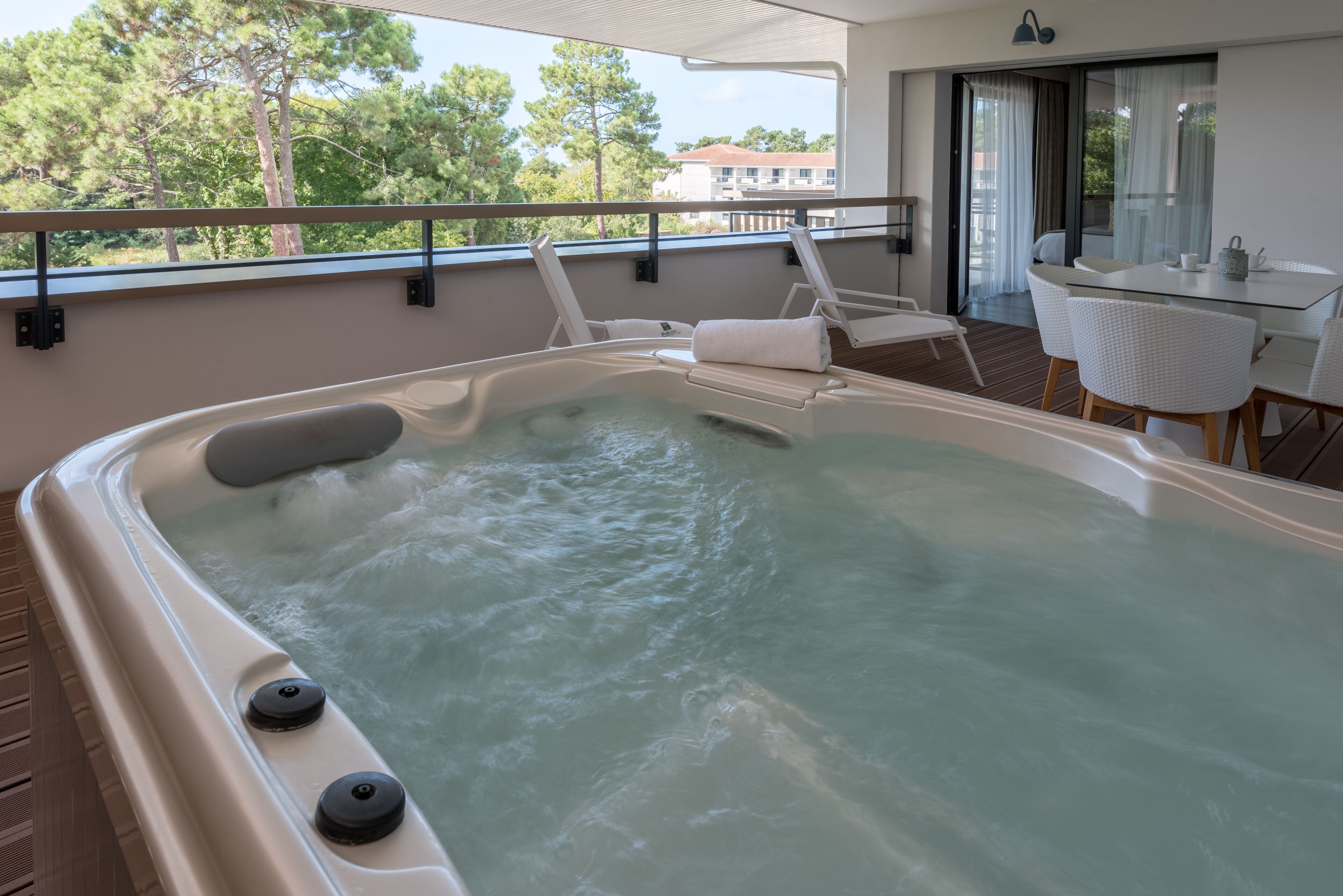A hot tub with a view of trees and a building in the background.