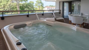 A hot tub with a view of trees and a building in the background.