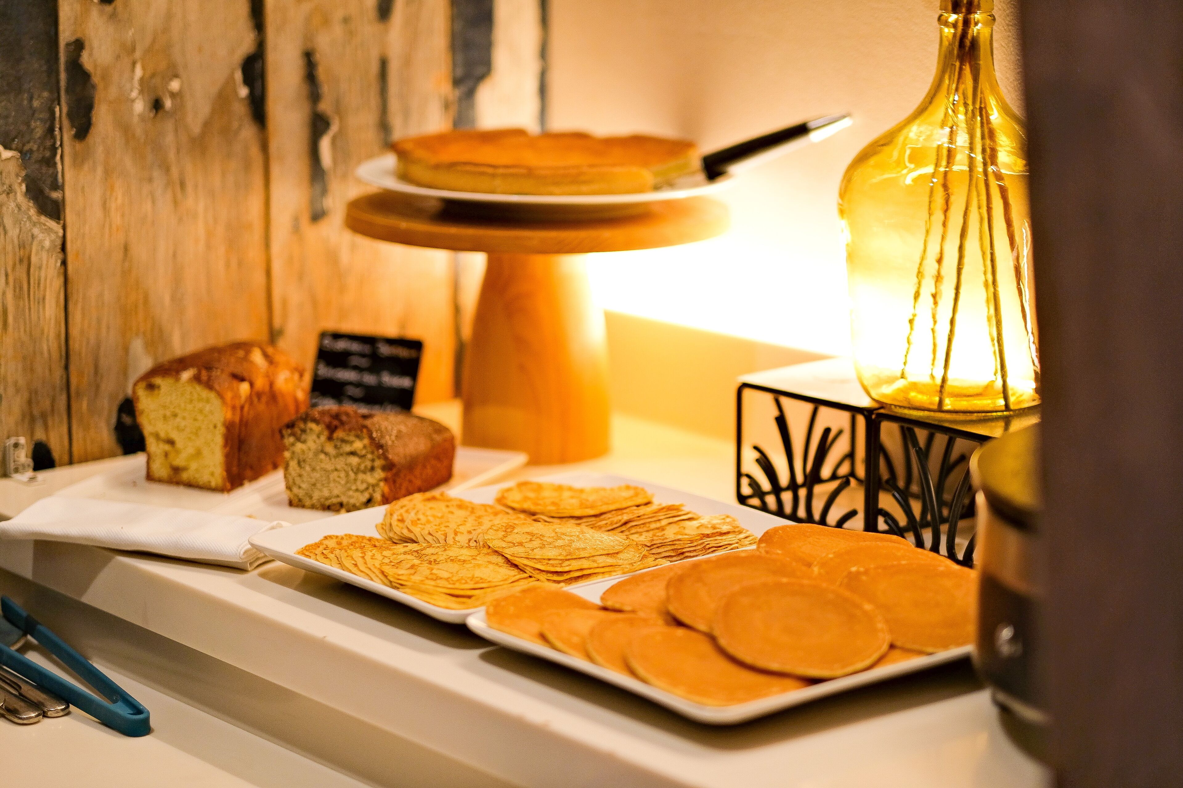 Um buffet de café da manhã com diversos pães, bolos e panquecas.