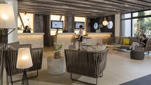 A modern reception area with a wooden ceiling, comfortable seating, and a large window providing natural light. - Hôtel & Spa - Thalazur Arcachon (Arcachon)