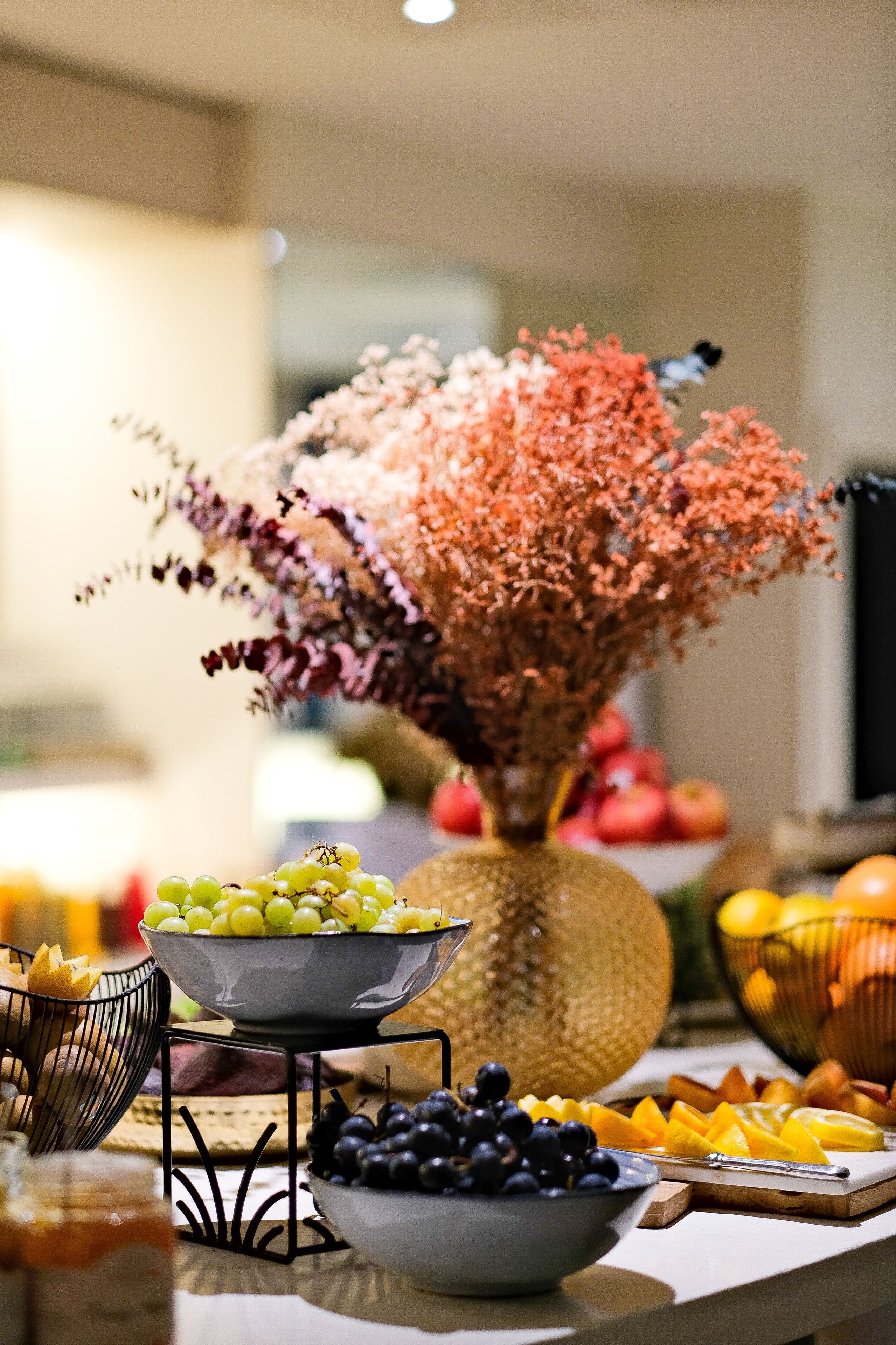 Una mesa con diversas frutas y un jarrón decorativo.