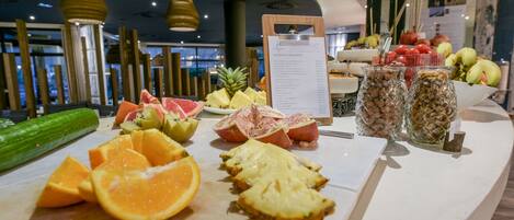 Una exhibición de frutas con piña, naranjas y manzanas sobre un mostrador.