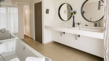 A modern bathroom with a bathtub, two sinks, and two large mirrors.