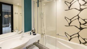 Une salle de bain moderne dotée d’une douche à parois de verre, d’une grande baignoire blanche et d’un meuble-lavabo à deux vasques.