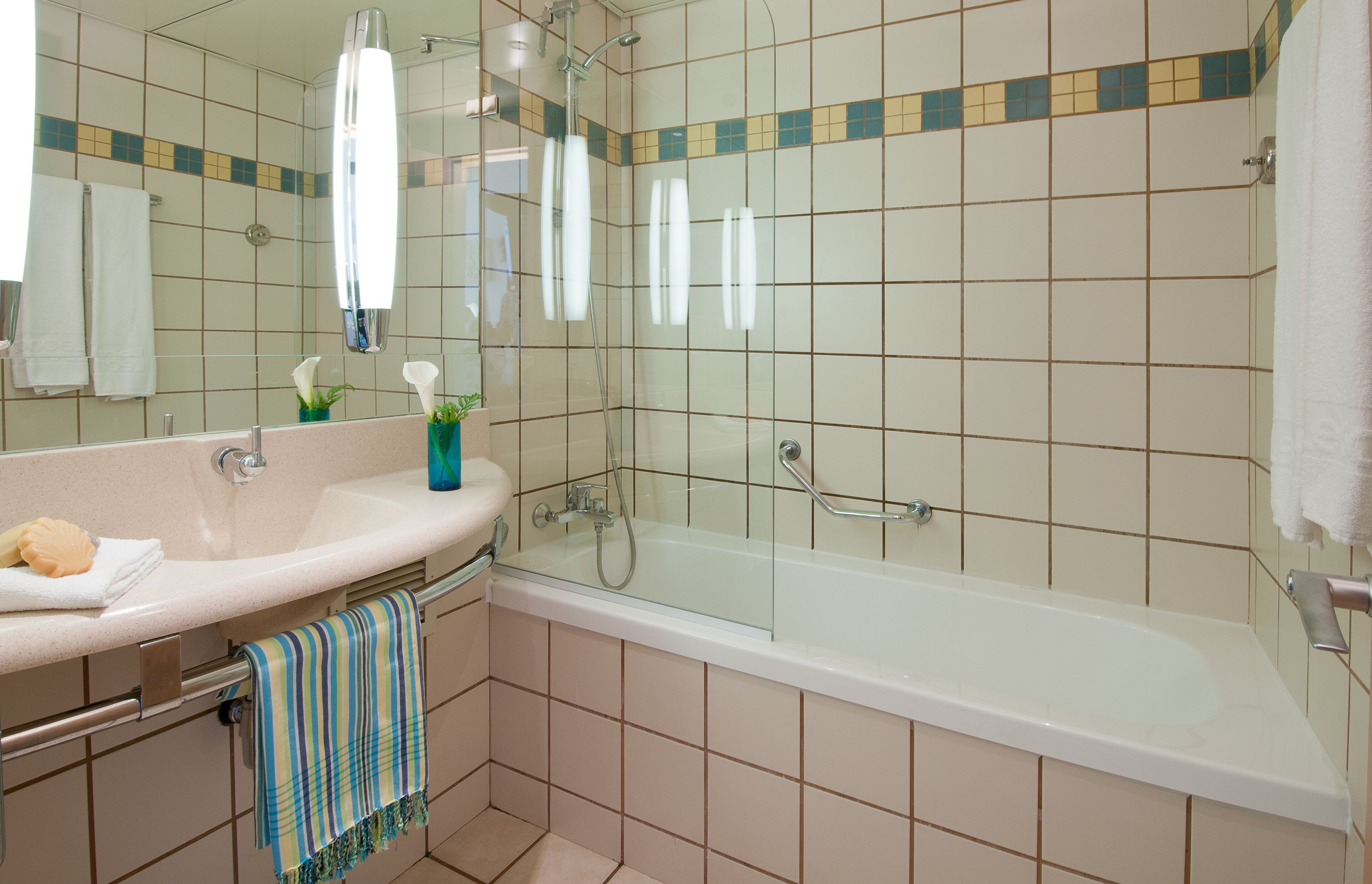 A bathroom with a sink, mirror, and shower.