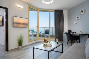 Uma sala de estar moderna com uma grande porta de vidro deslizante para uma varanda, uma área de jantar e uma televisão de tela plana na parede.
