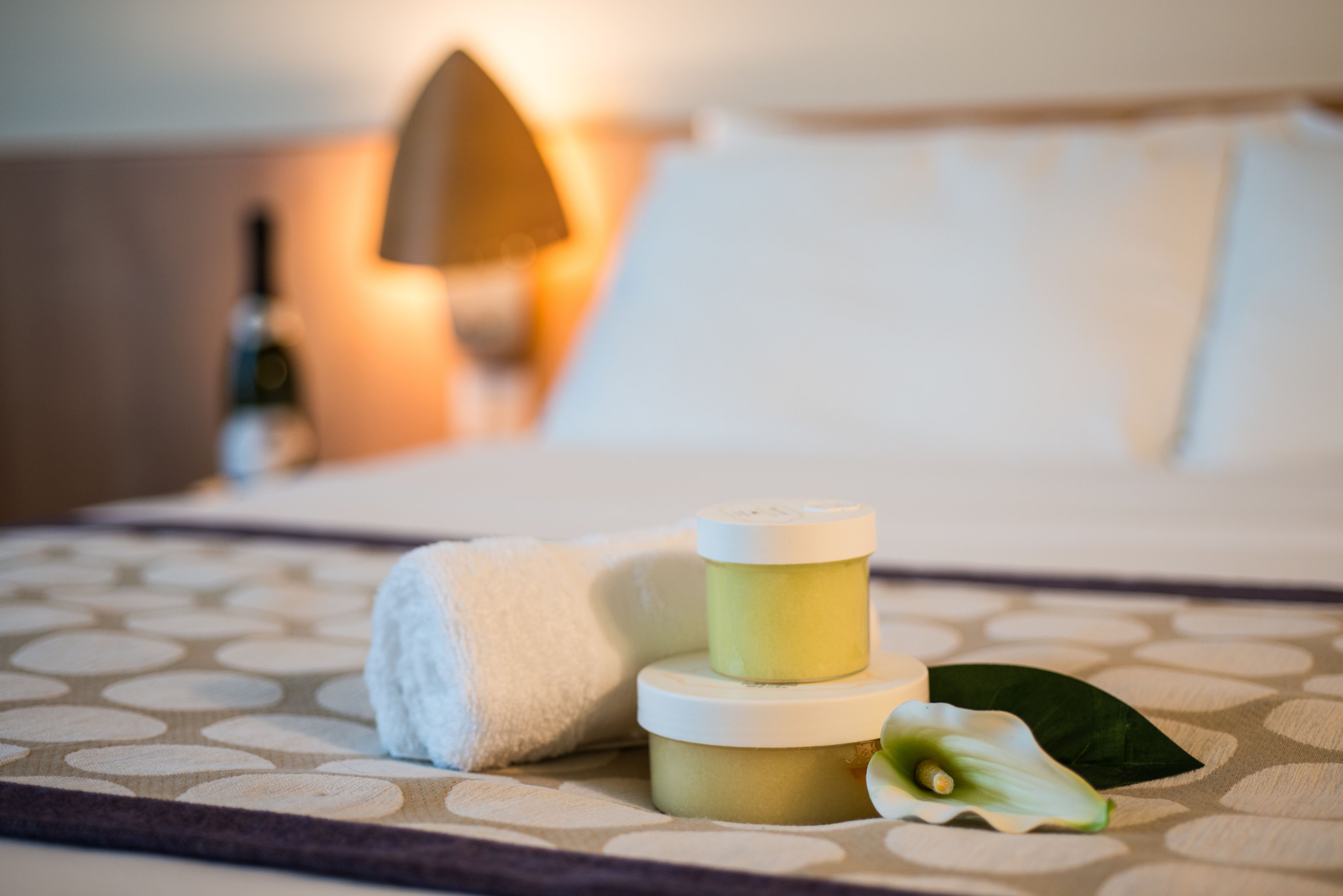 Une salle de bain bien rangée, avec une serviette, un pot de crème et une fleur posés sur une surface à motifs.