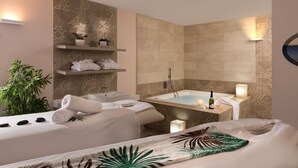 A modern bathroom with a bathtub, a sink, and a shelf with towels and plants. - Leonardo Plaza Dead Sea (Tamar)