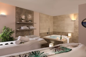 A modern bathroom with a bathtub, a sink, and a shelf with towels and plants.