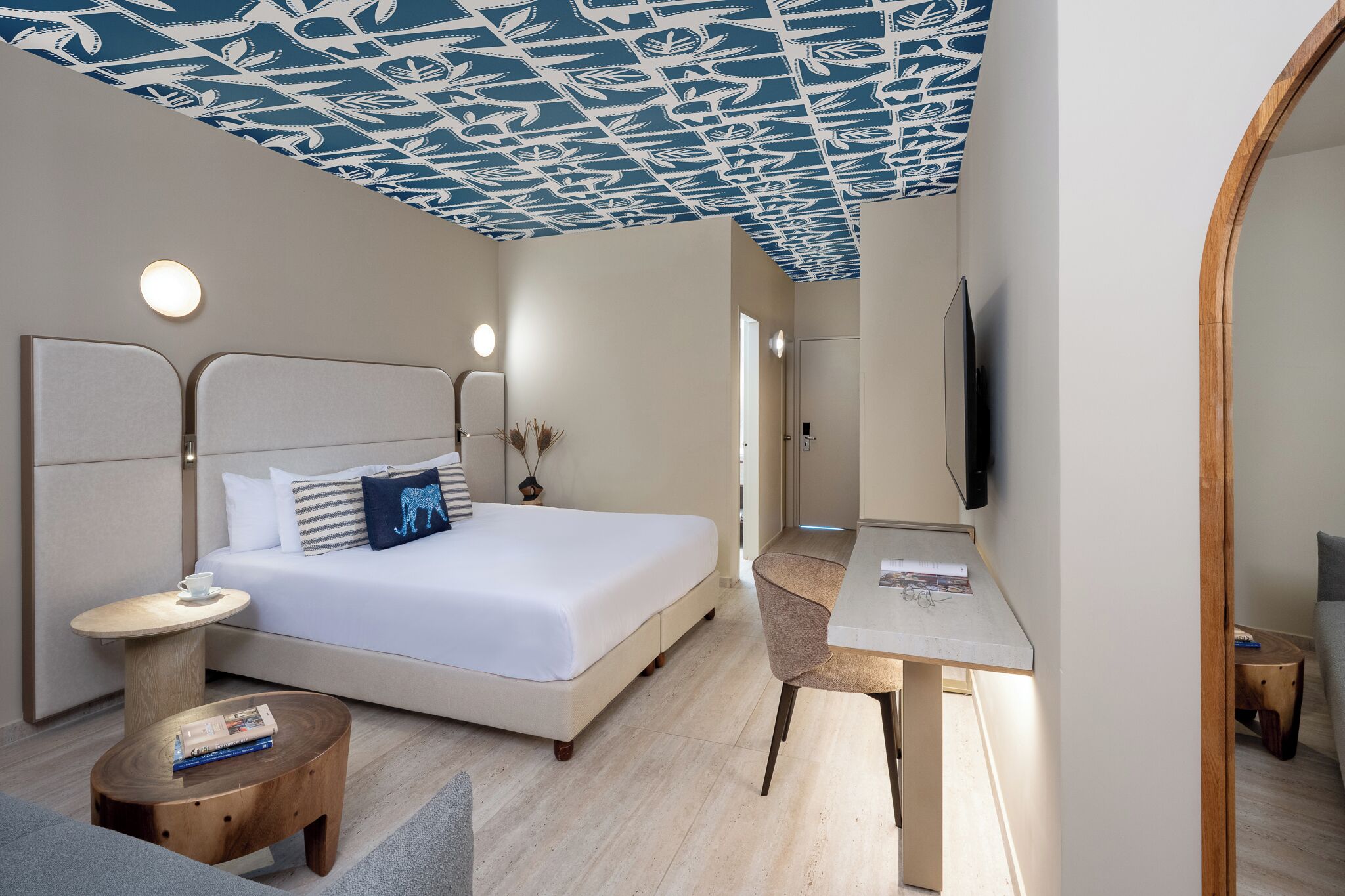 Una habitación de hotel moderna con cama, mesita de noche, silla, escritorio y televisor.