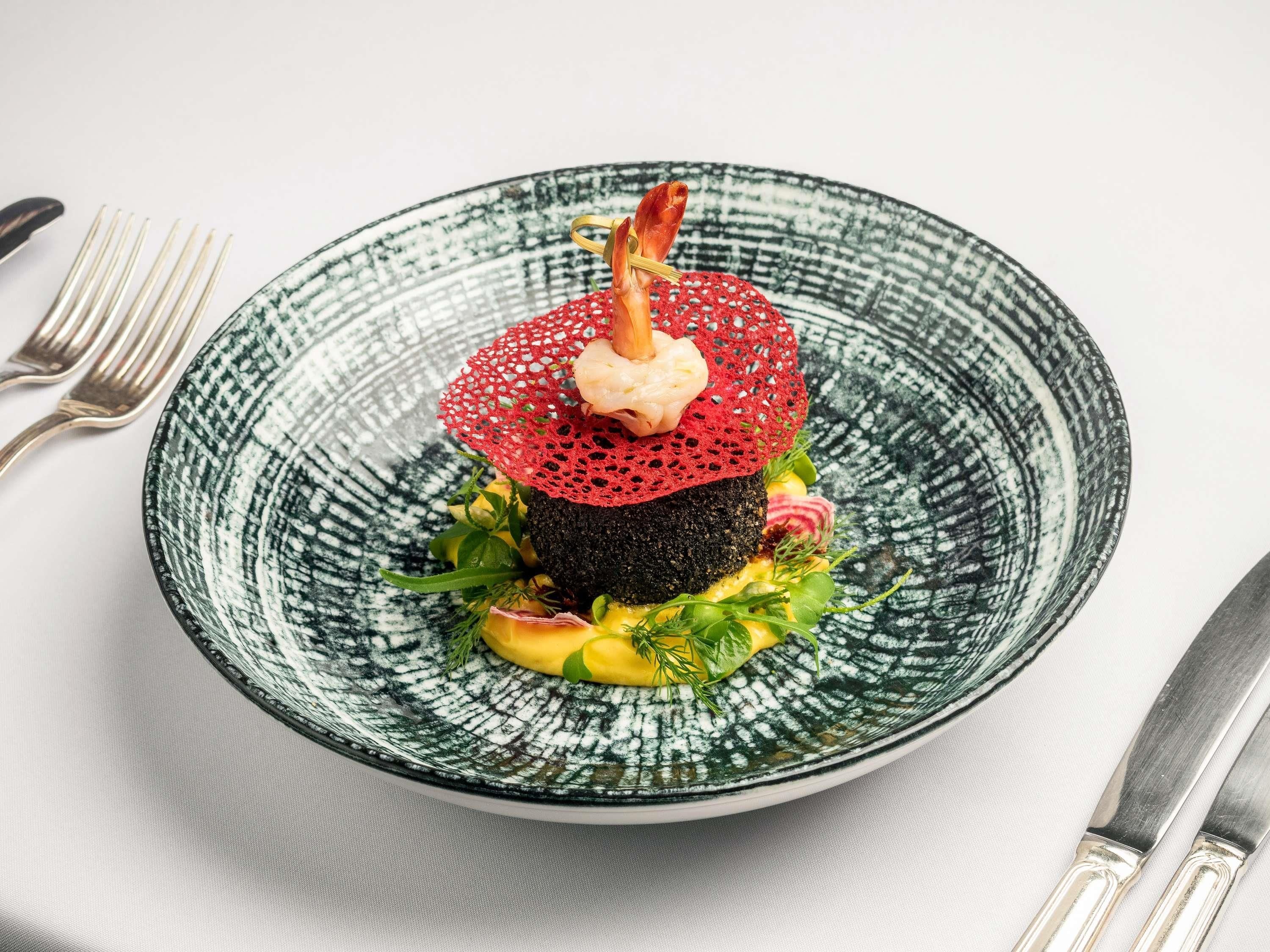 A plate with a unique dish, a fork and knife on the side.