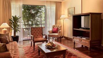 A well-furnished living room with a sofa, two armchairs, a coffee table, a television, and a potted plant.
