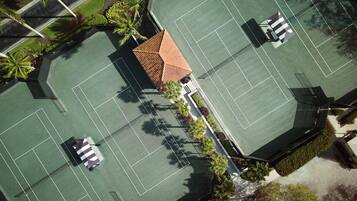 Vue aérienne d’un complexe de courts de tennis comprenant plusieurs terrains, un bâtiment central et des espaces verts environnants.