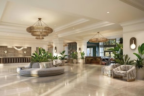 A spacious lobby with a large seating area, multiple hanging chandeliers, and potted plants. - The Ritz-Carlton Naples, Tiburón (Naples)