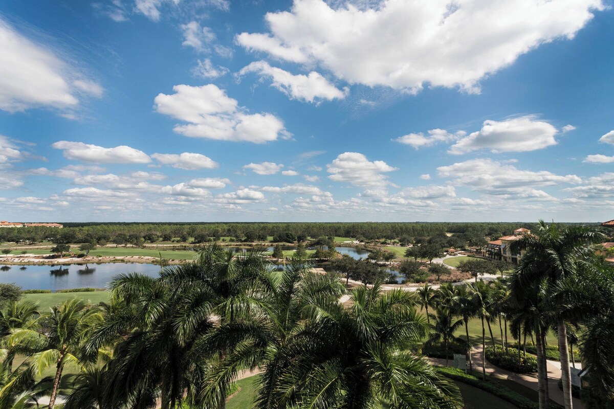 A resort with a golf course, palm trees, and a large body of water.