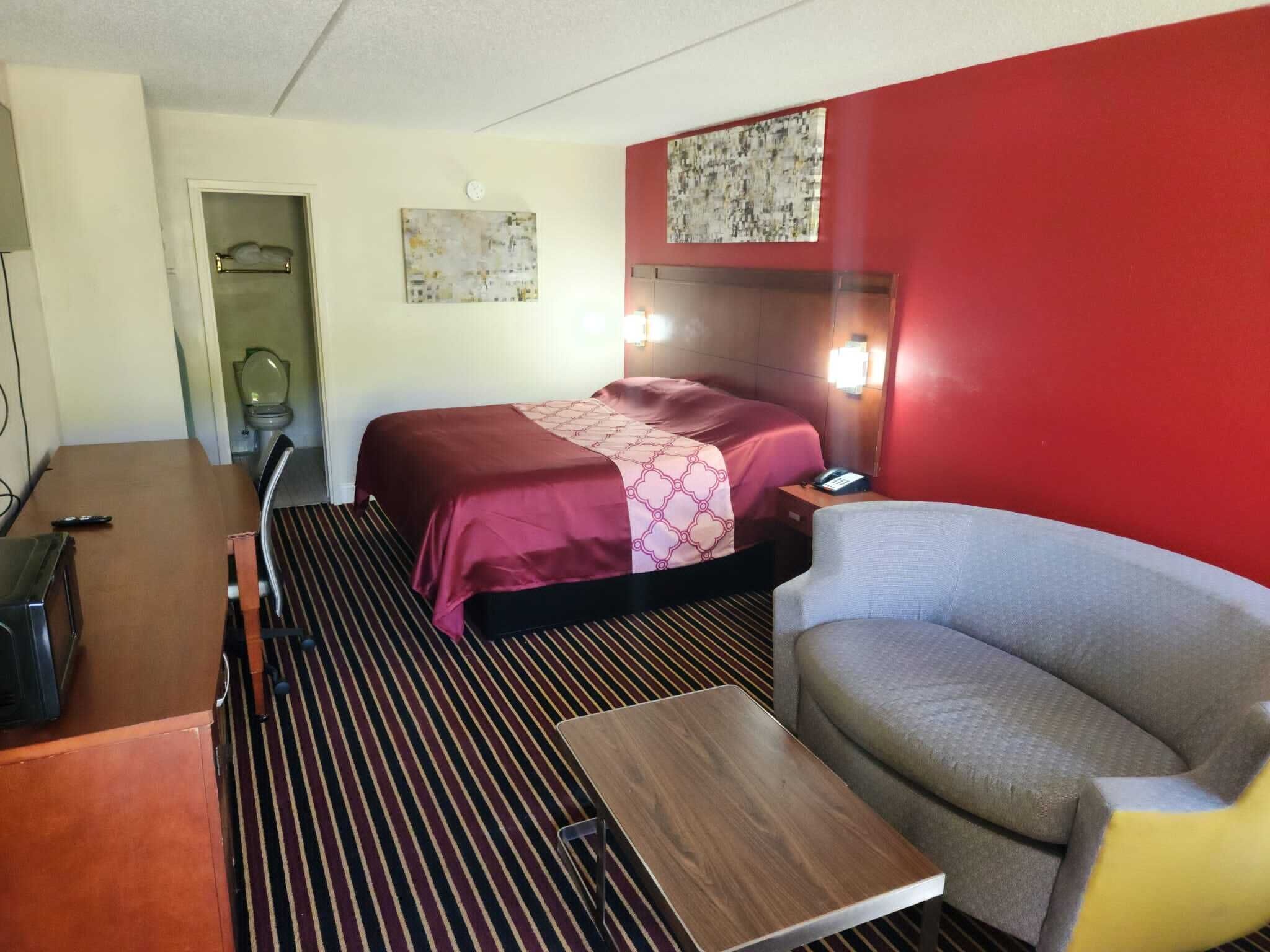 A hotel room with a bed, a desk, a chair, and a bathroom.