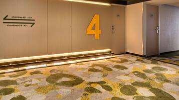 A hotel corridor with directional signs for rooms 401-417 and 418-433, a large '4' on the wall, and a patterned floor.