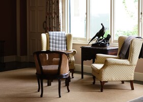 A room with two armchairs, a small table, and a decorative statue.