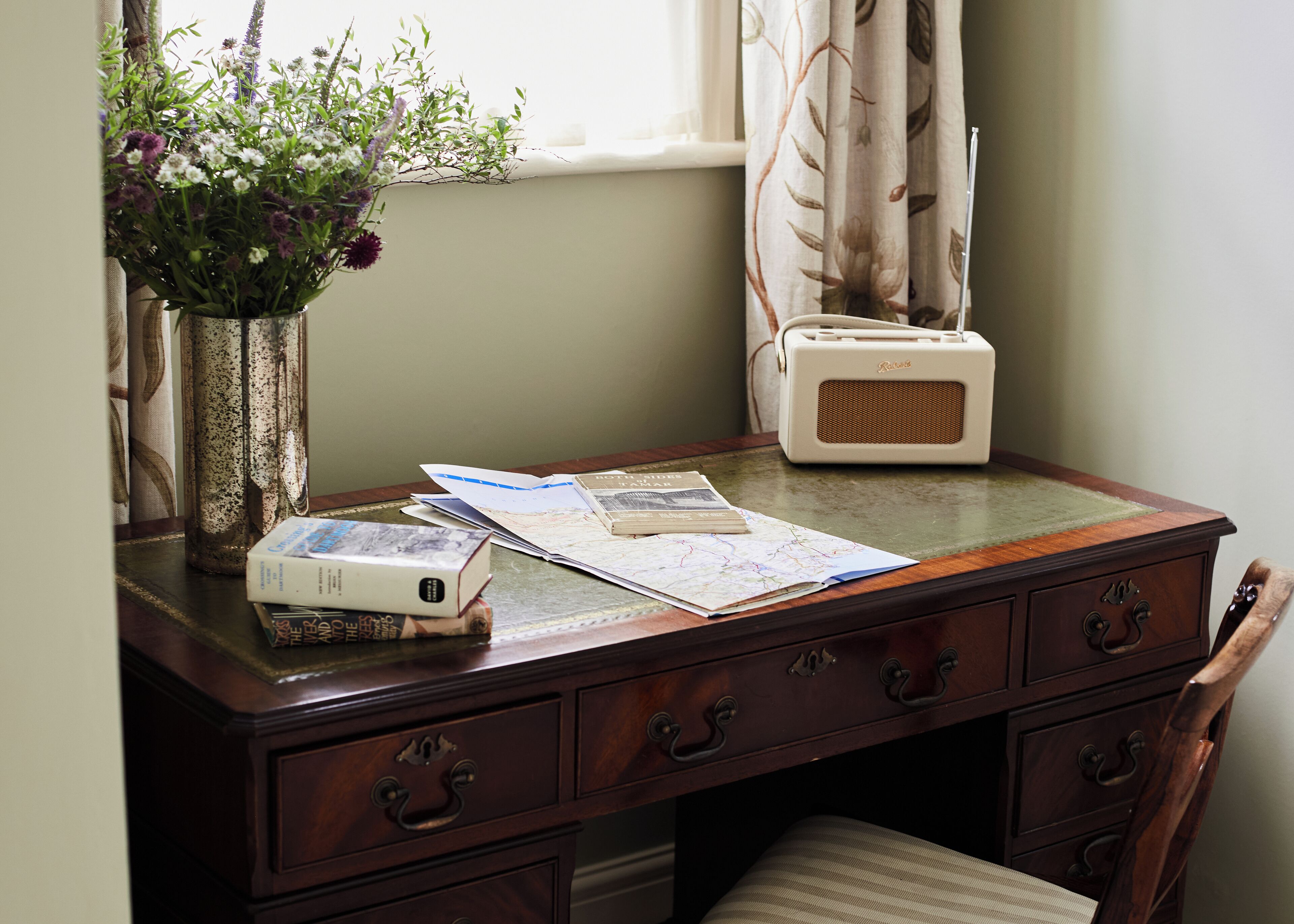 A wooden desk with a radio, books, and a map.