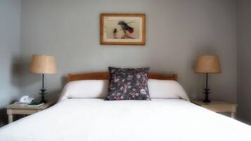 A neatly made bed with white linens, a floral pillow, and two bedside lamps on either side.