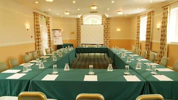 A conference room with a long table, chairs, and a projector screen.