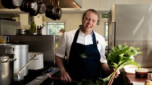 A chef in a kitchen holding fresh rhubarb. - The Arundell  (Lifton)