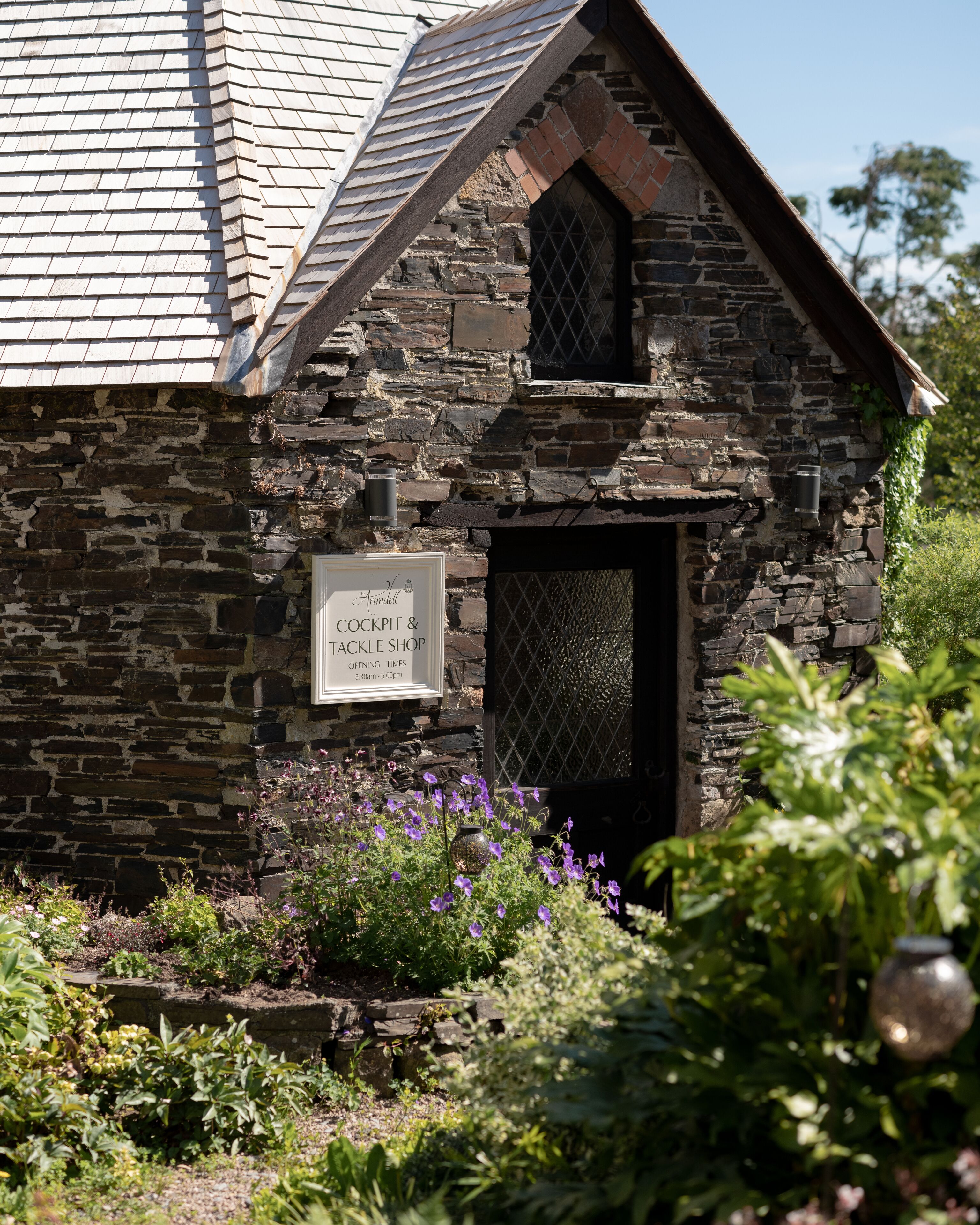 A stone building with a sign for 'Armell Cockpit & Tackle Shop'.