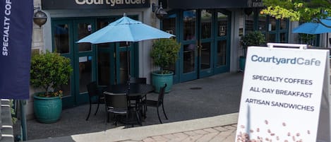 A Courtyard Cafe with outdoor seating, a signboard, and potted plants.