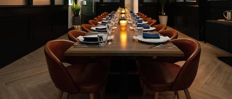 Una larga mesa de comedor preparada para una comida, con sillas a ambos lados.