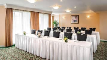 A conference room with a long table, multiple chairs, and a potted plant.