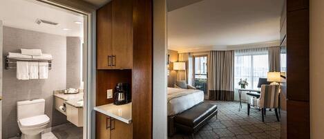 Una habitación de hotel con baño, cama, escritorio y zona de estar.