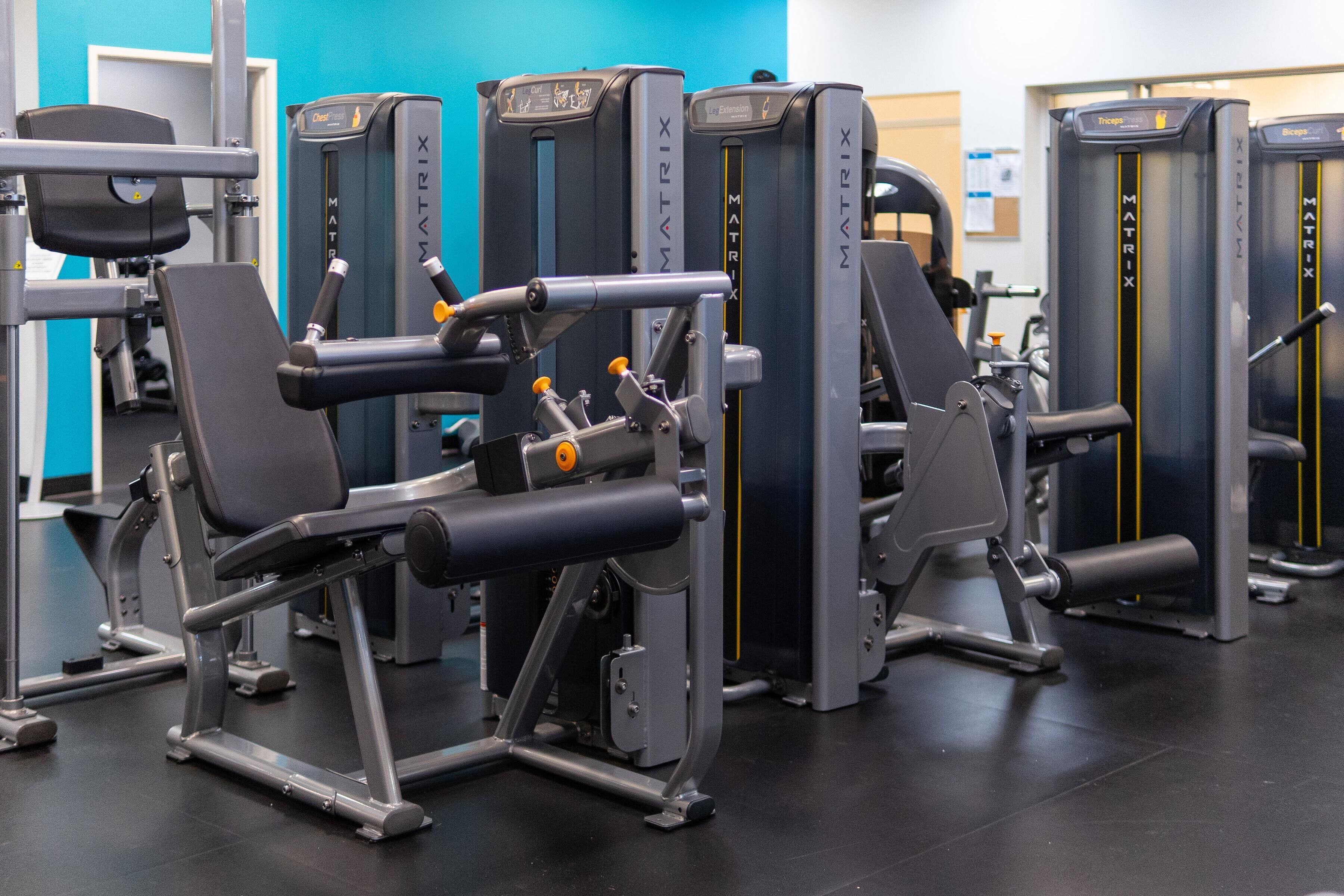 A gym with various exercise machines, including a chest press machine and a leg press machine.