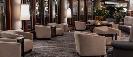 A hotel lobby with multiple seating areas, a chandelier, and large windows.