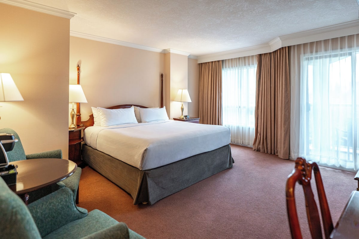 A hotel room with a bed, two bedside tables with lamps, a chair, and a small table.