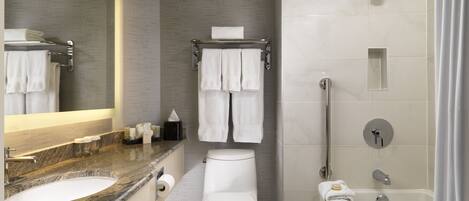 A modern bathroom with a marble countertop, a toilet, a shower with a handheld showerhead, and a bathtub.