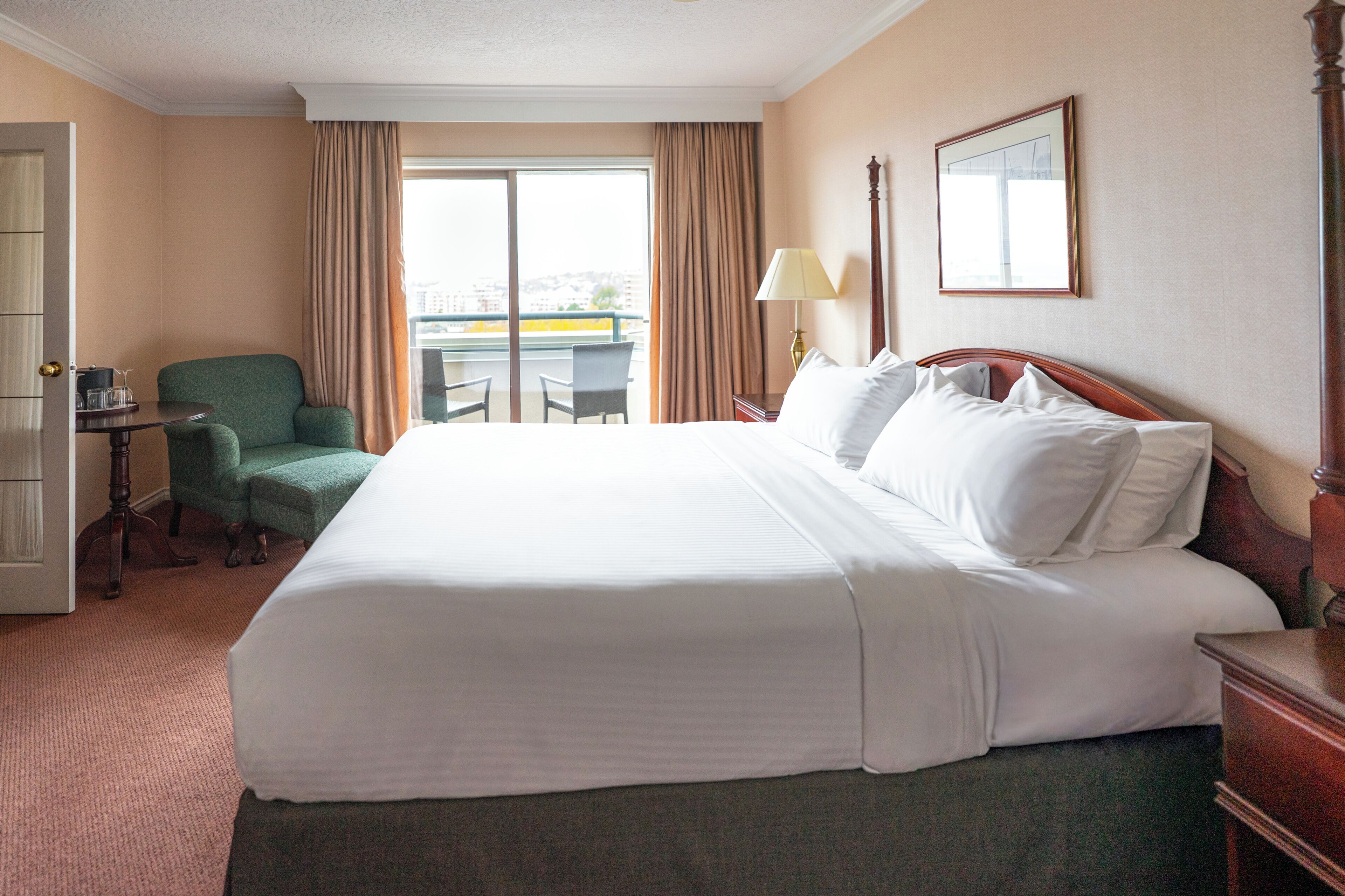 A hotel room with a large bed, a chair, a desk, a lamp, and a window with curtains.