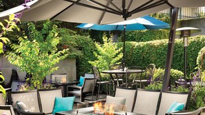 Une terrasse extérieure avec une table à foyer, des chaises et des parasols.