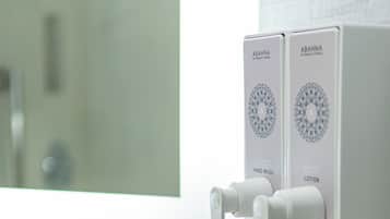 Une salle de bain équipée d’un distributeur de savon liquide et de lotion, d’un porte-serviettes avec des serviettes pliées, et d’un miroir qui reflète la pièce.