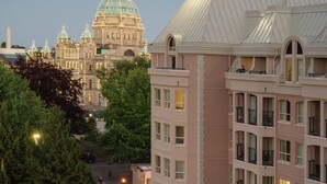 Un hôtel au design moderne, doté d’une terrasse sur le toit avec des sièges et offrant une vue sur un bâtiment historique en arrière-plan.