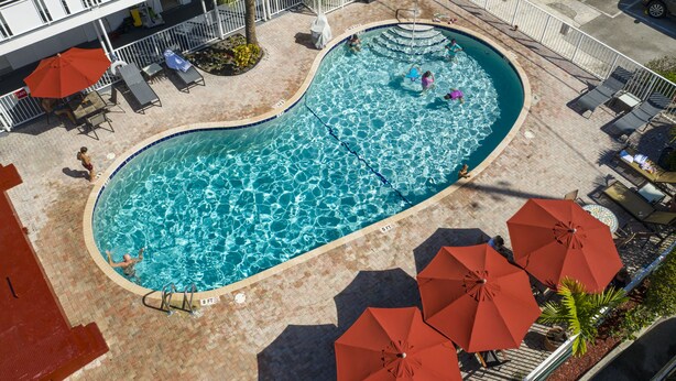 Una piscina al aire libre de diseño curvo, rodeada de sillas de descanso y sombrillas.