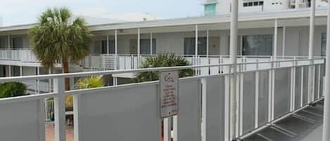 A hotel with a pool area, multiple balconies, and a sign indicating a covered outdoor area.