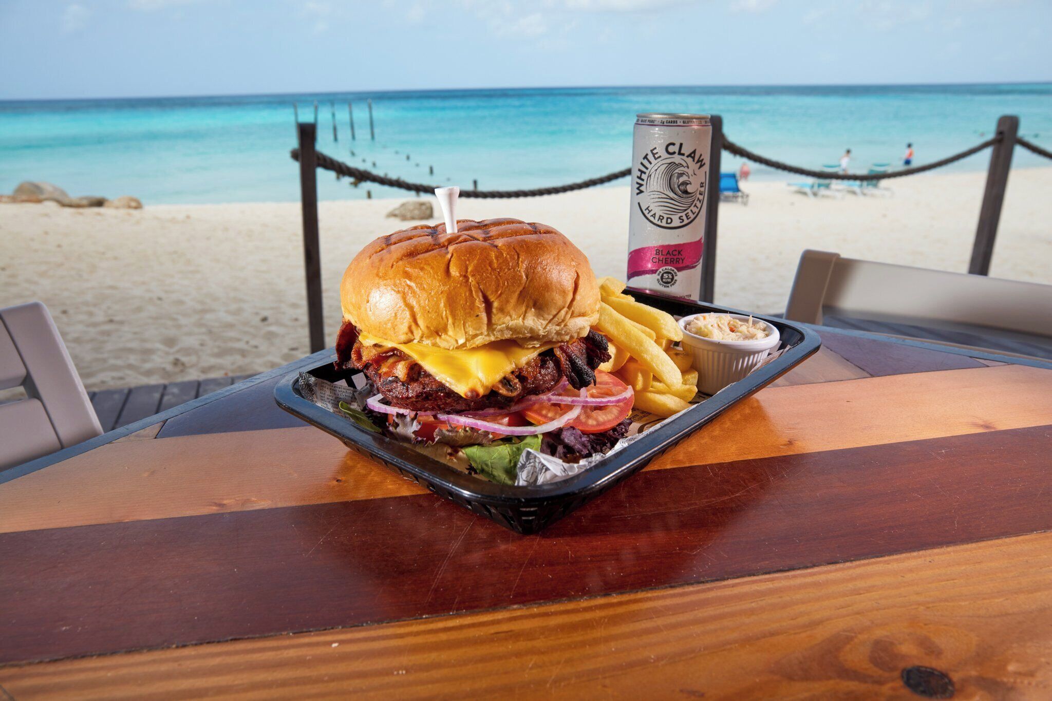 A meal on a wooden table with a view of a beach and ocean.