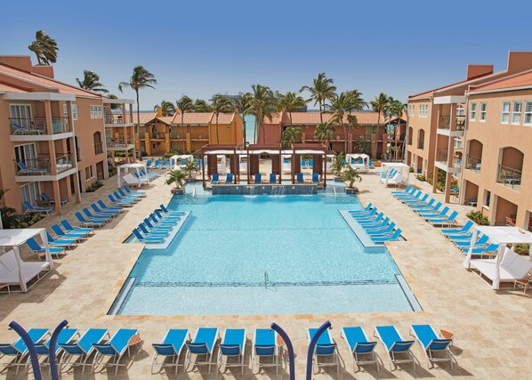 Relax by the central pool surrounded by sun loungers and two-story buildings with balconies.